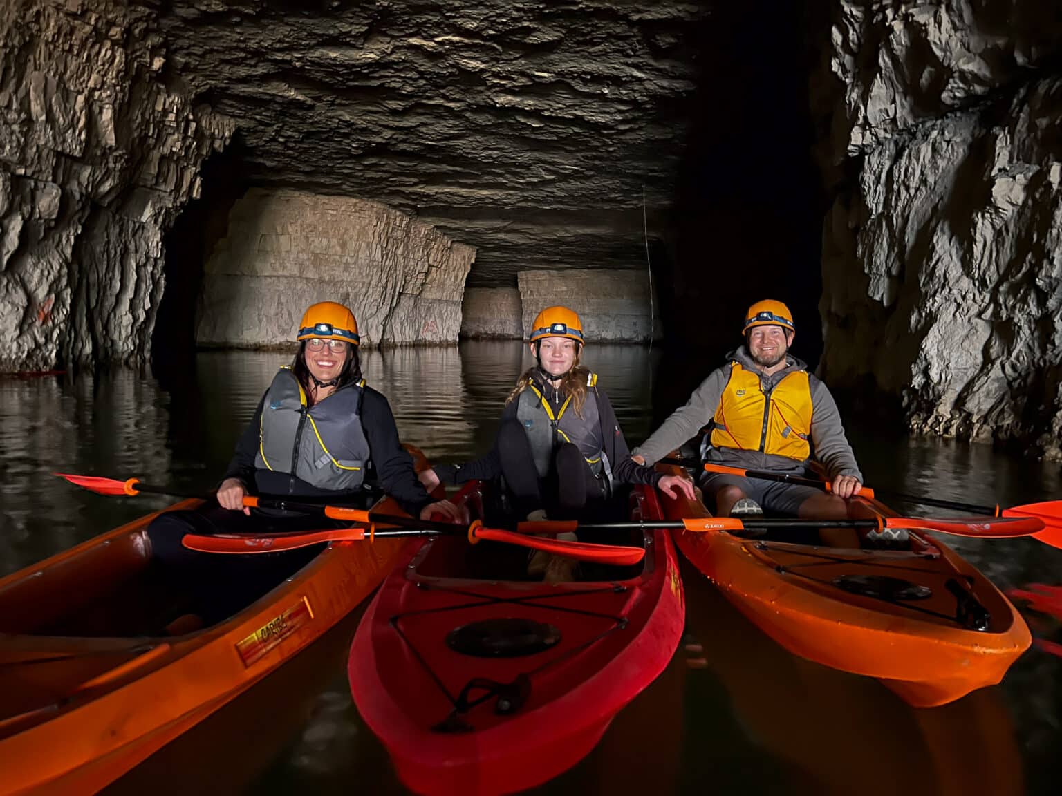 Three people in kayaks in a cave.