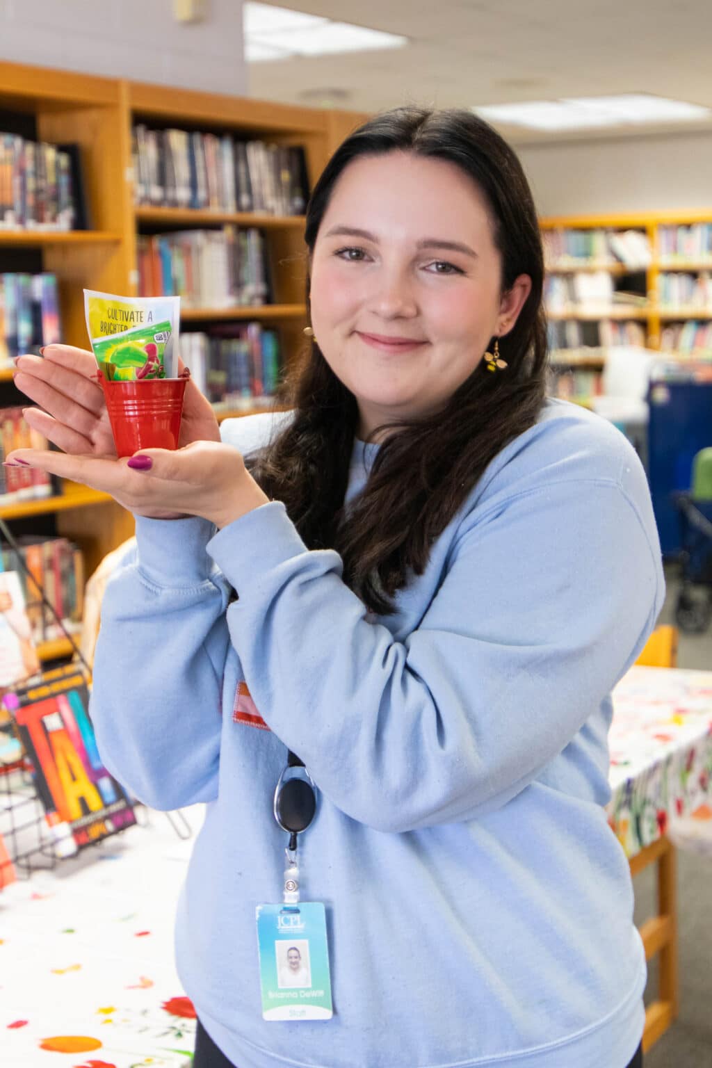 Teen Outreach Librarian Brianna shows off a craft students made at a middle  school library.