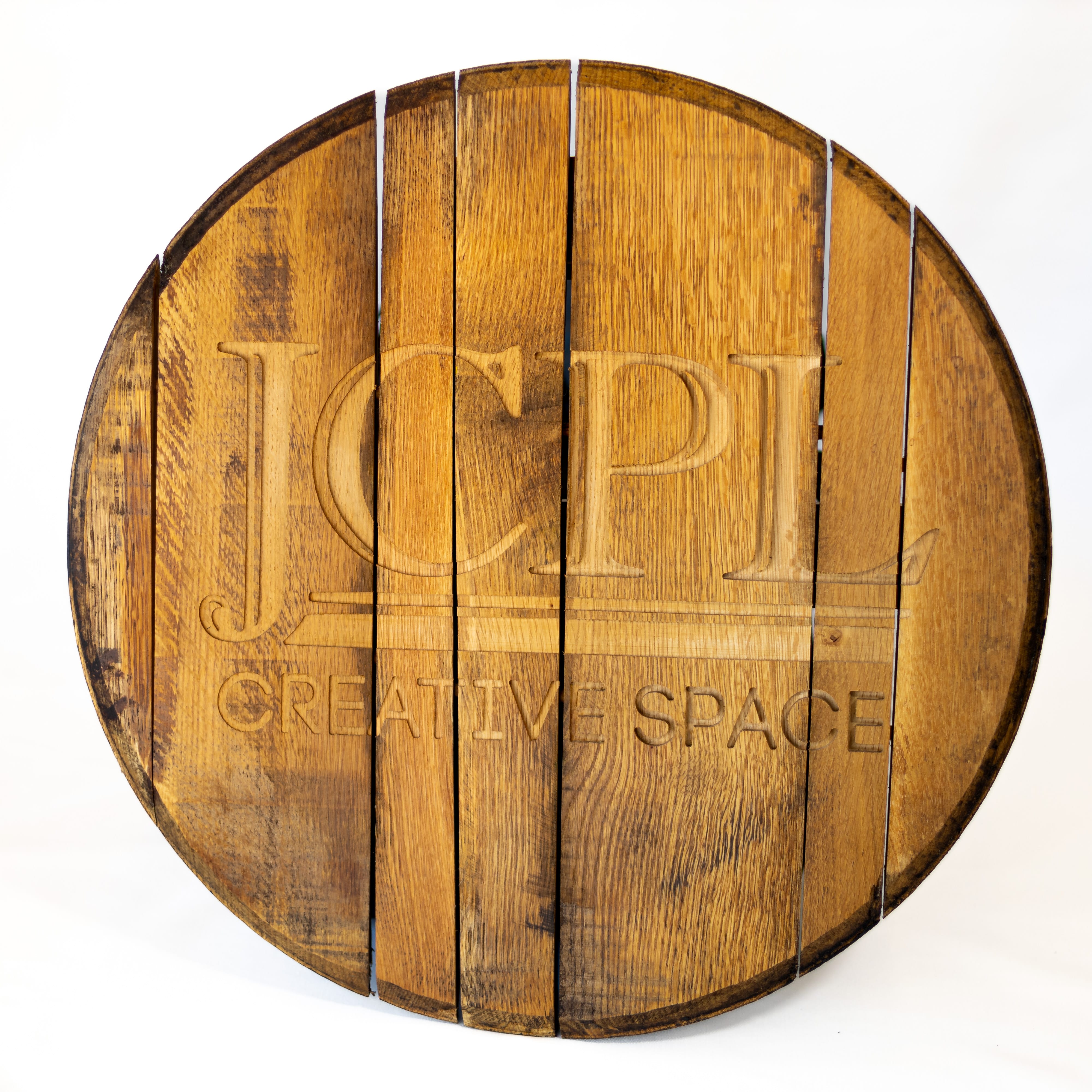 A bourbon barrel head with JCPL cut into the top.