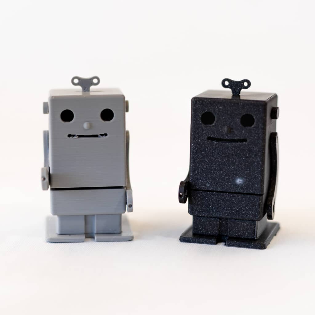 One small gray and one small black robot figurine.