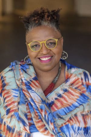 Photo of Crystal Wilkinson, an African American woman wearing yellow glasses and a blue and orange top.