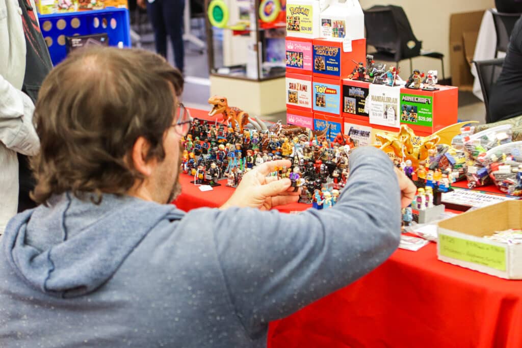 A vendor from the 2022 Comic Surge arranges minifigs on a table.