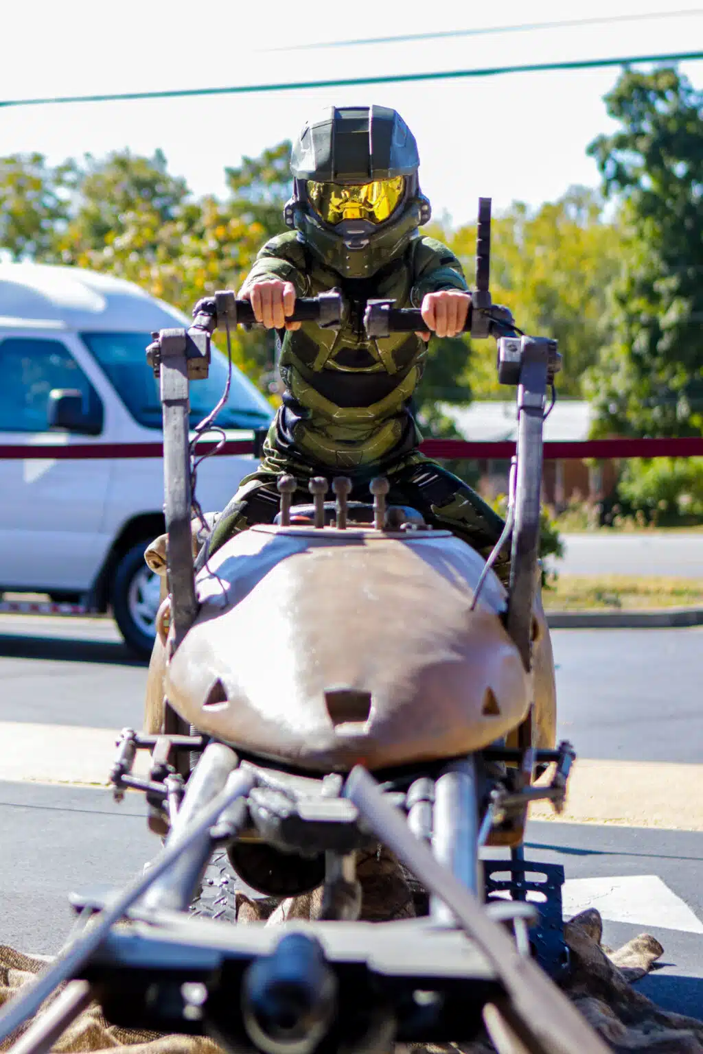 A young cosplayer dressed as Master Chief from Halo rides on a speeder from Star Wars.