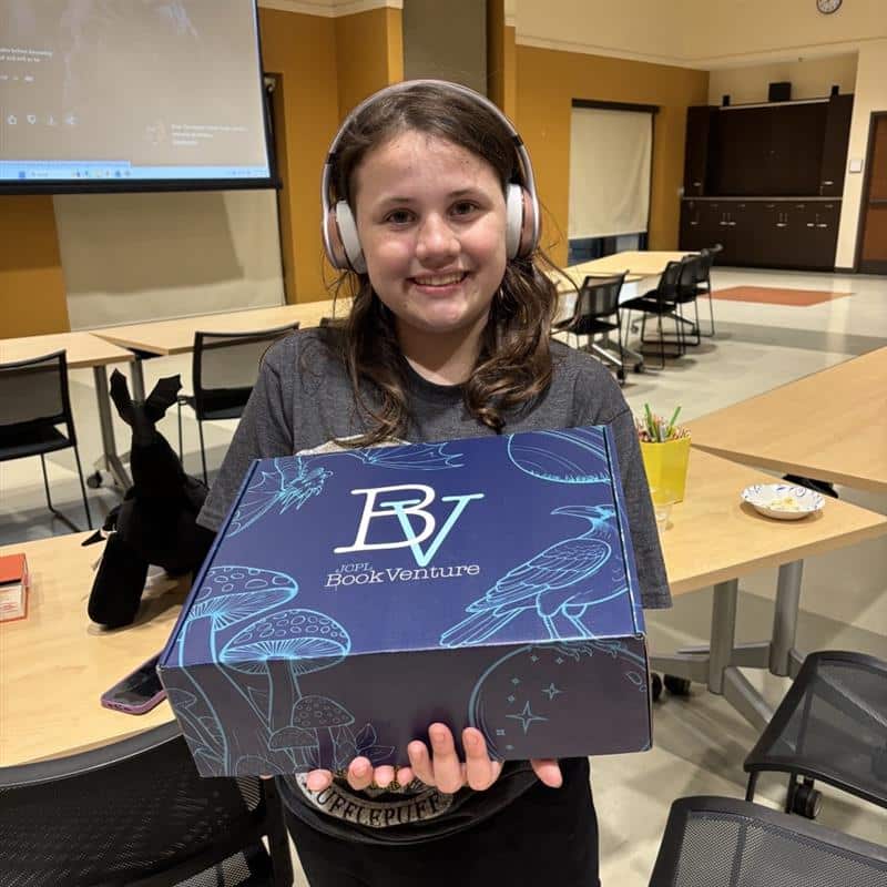 A teen girl holds a BookVenture box.