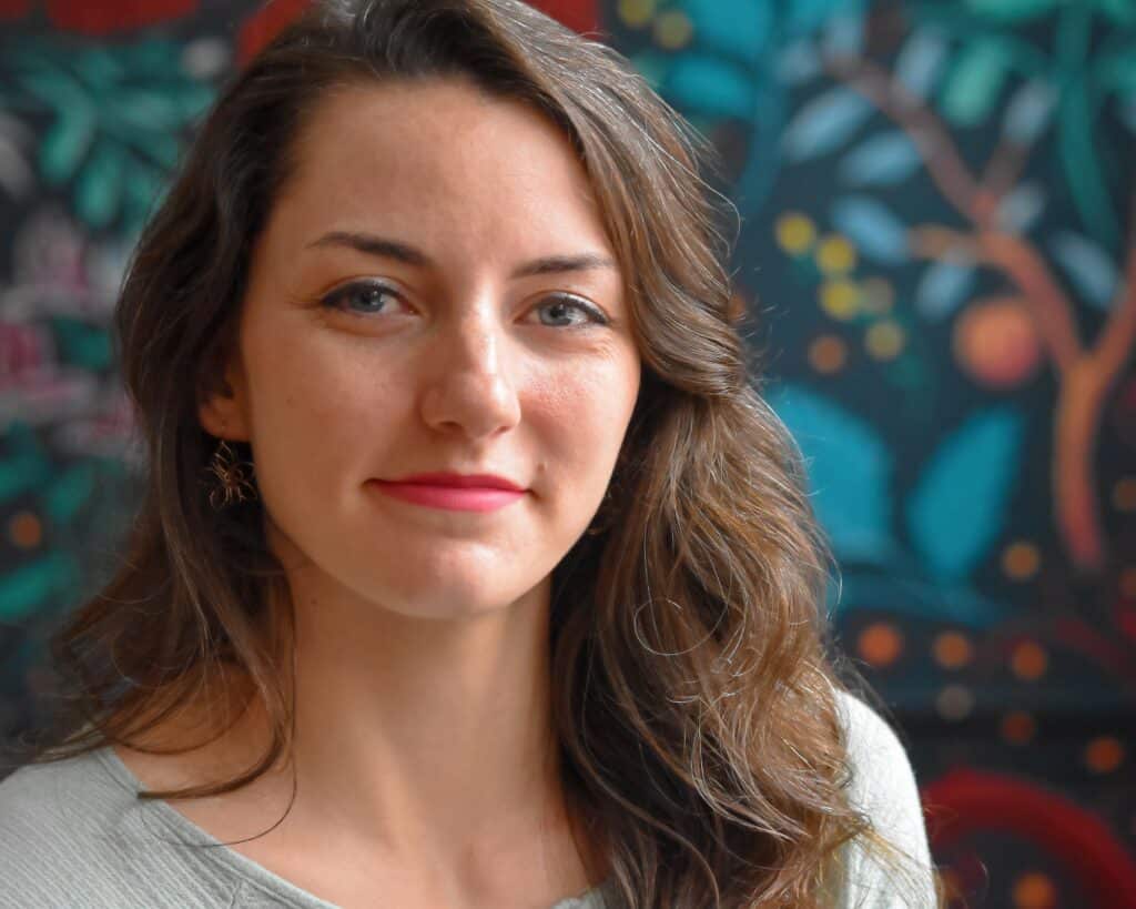 Headshot of author Kaitlyn Hill, a young white woman with long wavy brown hair.