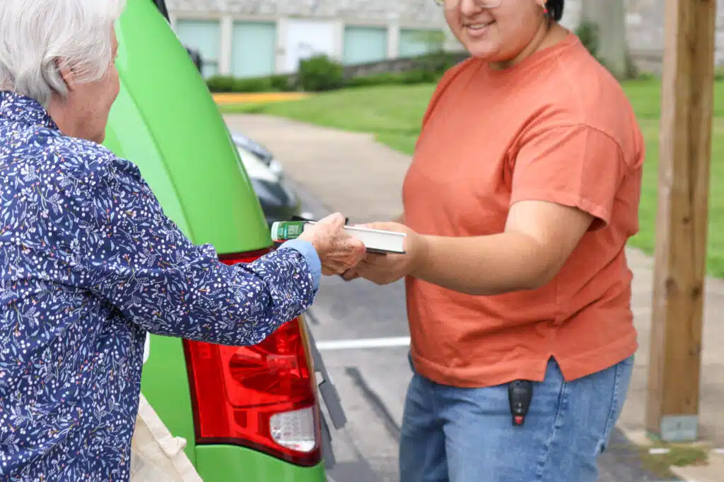 A library volunteer delivers a book to a homebound customer.