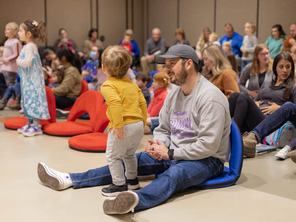 A dad and toddler interact during a library storytime.