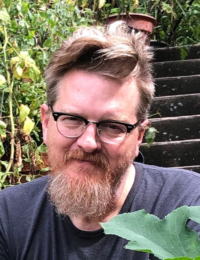 Headshot of author Robert Gipe with steps and greenery in the background.