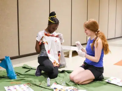 Two teen girls tie dye a t-shirt.