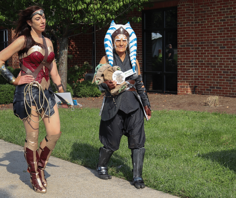Les Lehman cosplaying as Ahsoka Tano for Comic Surge. She's holding a baby Yoda and walking beside Wonder Woman.
