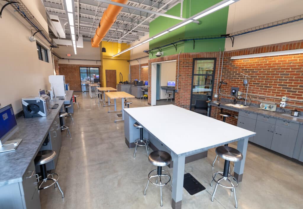The new JCPL Creative Space, a large, colorful room with big worktables, 3D printers, laser cutters, and other equipment.